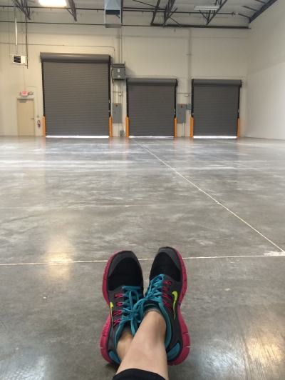 Empty warehouse interior viewed from the floor with the photographer's sneakers in the foreground
