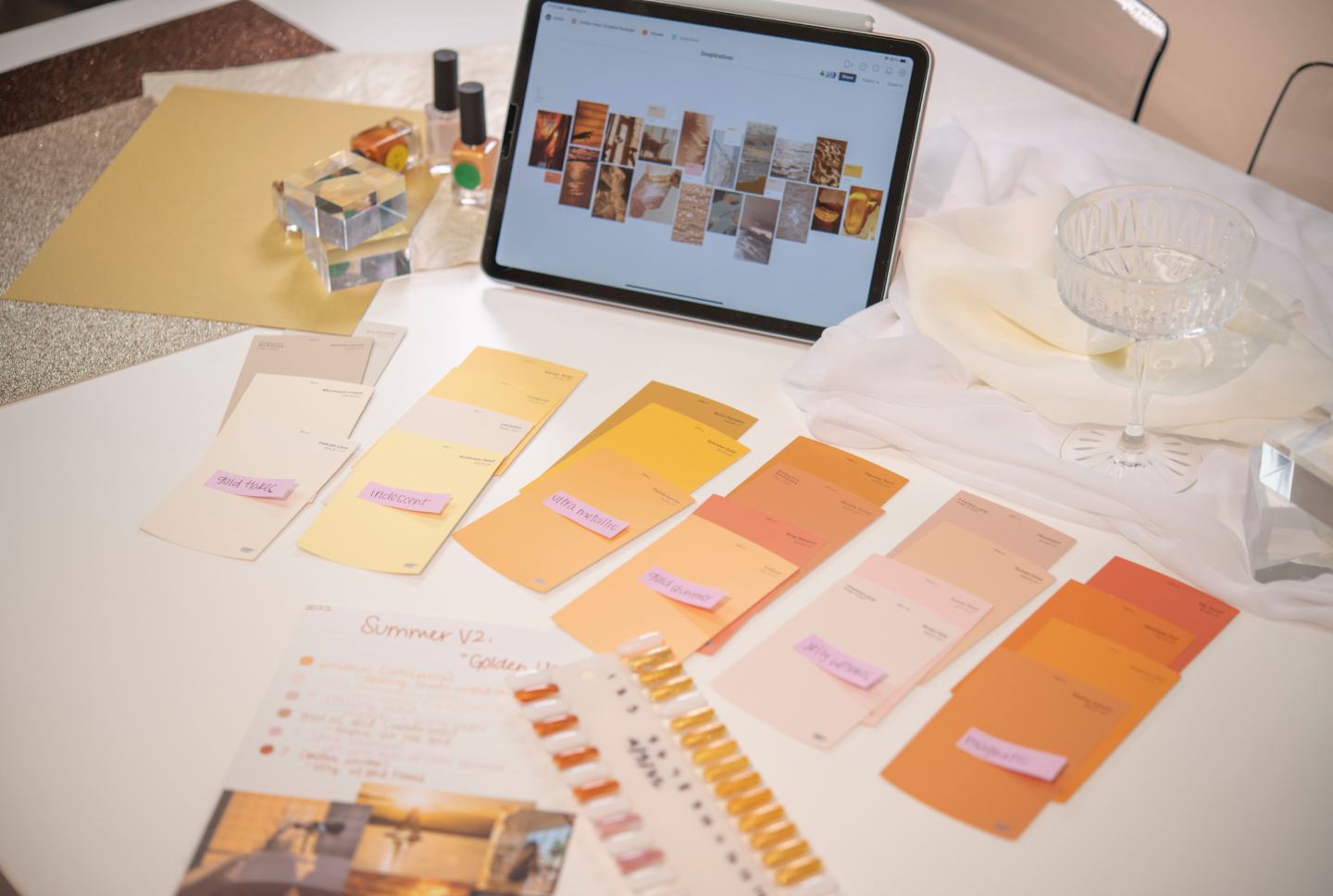 A design desk laid out with paint chips, color cards, and an iPad showing an inspiration mood board