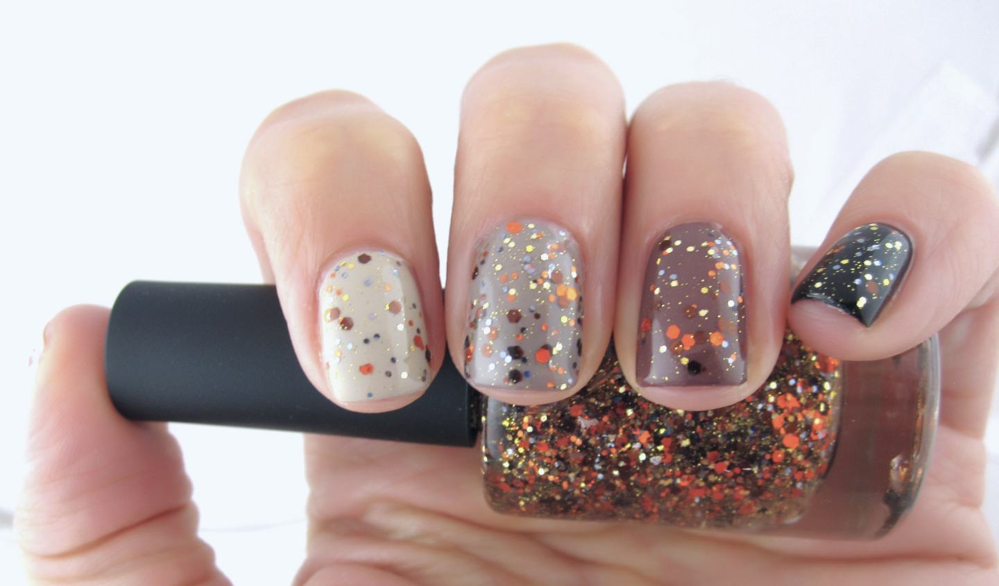 Manicure layering copper, gold, and orange glitter polish across four nails