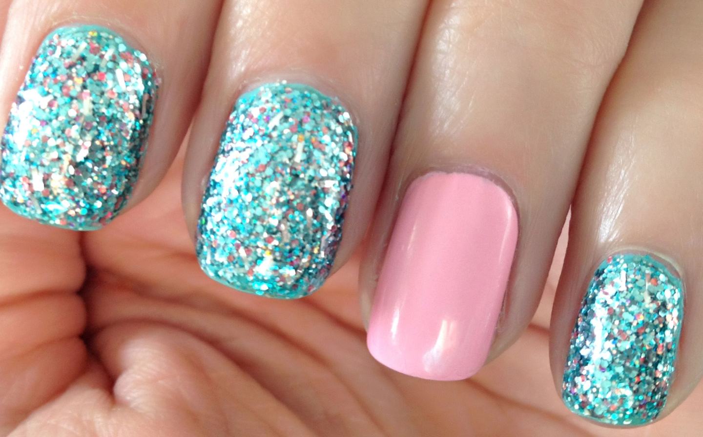 Manicure with teal-glitter polish on three nails and pink polish on the ring finger
